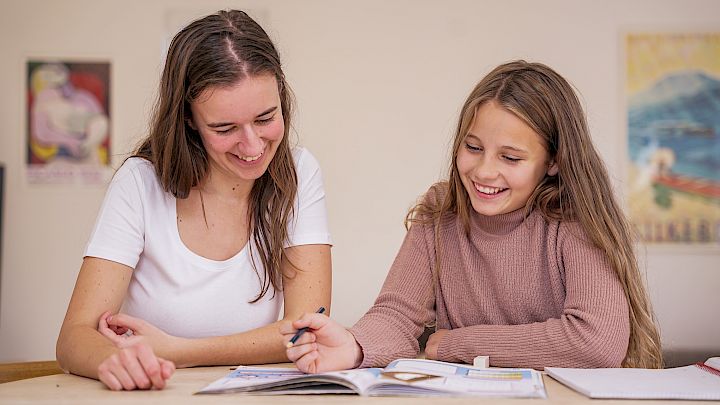 Mentor og elev læser i historiebog