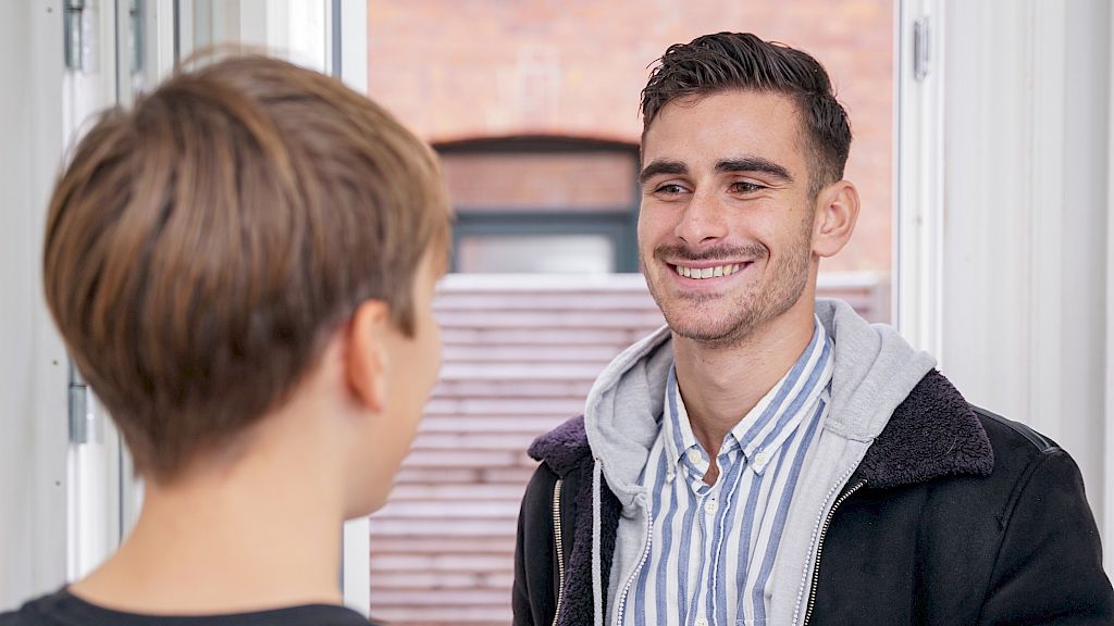 Mentor der ankommer glad til lektiehjælp med sin elev.