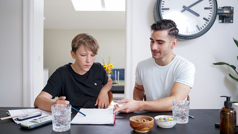 Lektiehjælper hjælper elev med skoleopgaver ved bord
