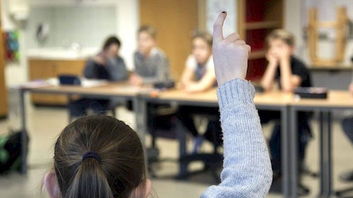 Barn rækker hånden op i skolen