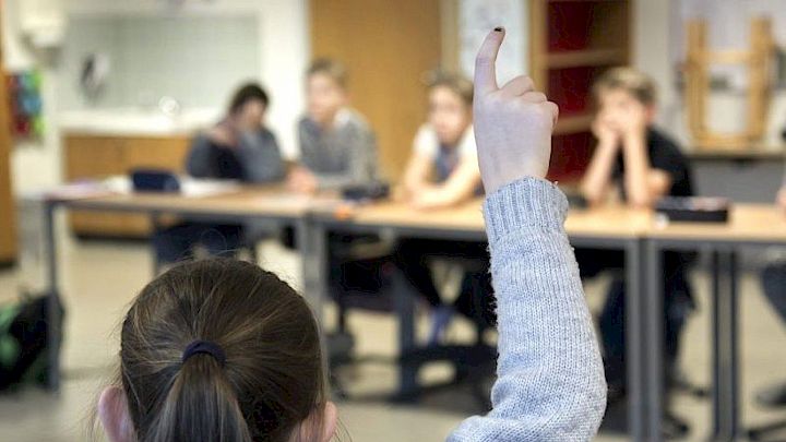 Barn rækker hånden op i skolen