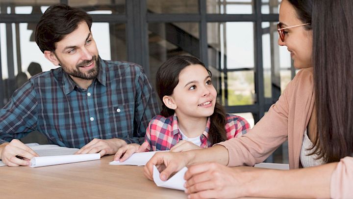 Piger sidder med forældre og er klar til skole-hjem-samtale