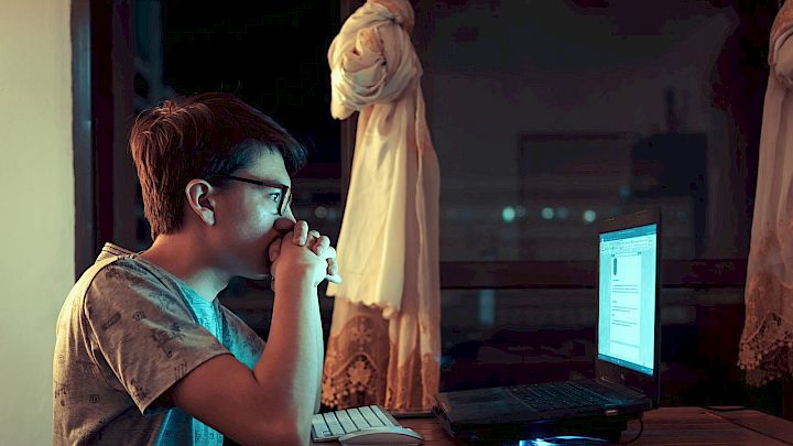 Dreng laver lektier på computer sent om aftenen