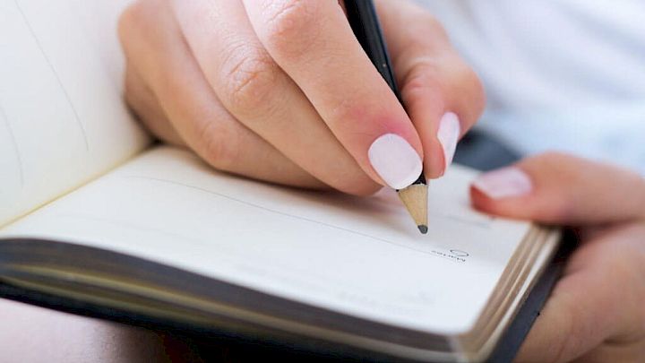 Elev skriver noter i sin notesbog
