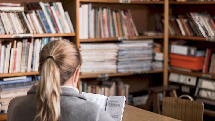 Elev sidder og læser på bibliotek