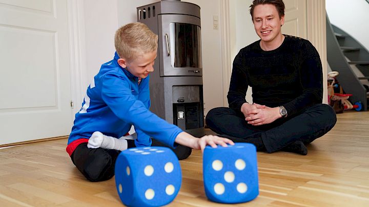 Dreng og mentor leger med to store terninger i matematik