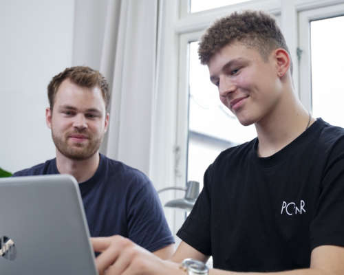 En mentor hjælper gymnasieelev med lektierne på computer